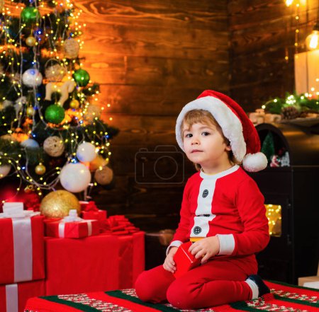 Photo for Lovely baby enjoy christmas. Santa boy little child celebrate christmas at home. Childhood memories. Family holiday. Boy cute child cheerful mood play near christmas tree. Merry and bright christmas. - Royalty Free Image