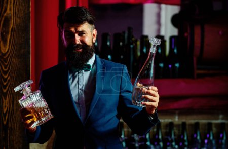 Foto de Barman barbudo guapo con barba larga y bigote con cara seria cóctel alcohólico hecho en traje vintage sobre fondo de bar - Imagen libre de derechos