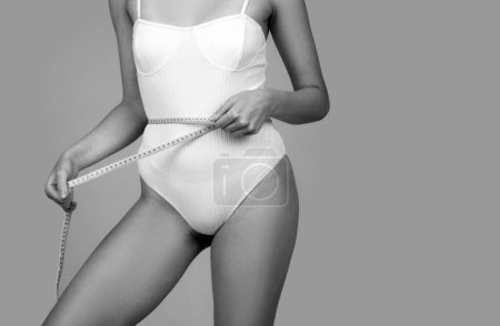 Photo for Concept of healthy eating and dieting. Young girl with perfect waist with a measuring tape. Waist shape - Royalty Free Image
