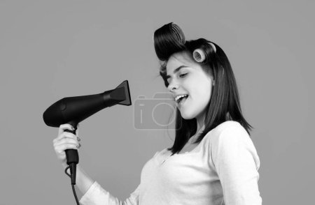 Photo for Woman with hair dryer. Beautiful girl with straight hair drying hair with professional hairdryer isolated in studio - Royalty Free Image
