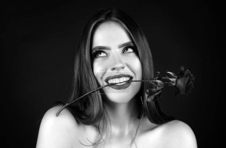 Photo for Rose flowers in a womans mouth. Red lips and rose. Beauty girl with sensual mouth. Sexy woman with red rose in teeth on black background. Woman day concept. Happy birthday day - Royalty Free Image