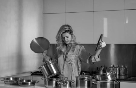 Foto de Mujer de casa sobrecargada. La mujer preparaba comida en la cocina por la mañana. olla de cocción - Imagen libre de derechos