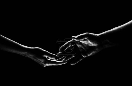 Téléchargez les photos : Two hands reaching toward. Helping hand outstretched for salvation on isolated black background. Close up of man and woman hand touch with fingers. Man and woman holding hands - en image libre de droit