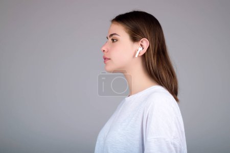 Téléchargez les photos : Femme écoutant de la musique avec des écouteurs. Fille avec écouteurs, écouteurs sans fil. Écouter de la musique en écoutant, studio. Écouteurs à l'oreille. Femme utilisant des écouteurs. Oreilles, écouteurs sans fil - en image libre de droit