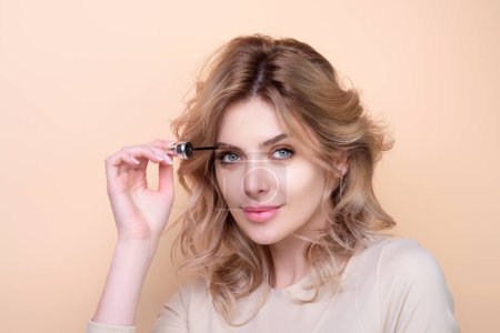 Photo for Beautiful woman applies brow gel with brows brush to her eyebrow. Studio portrait of young woman doing her eyebrow natural make up. Eyebrows make up concept - Royalty Free Image