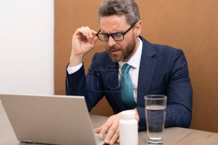 Photo for Business man feel pain holding glasses rubbing dry irritated eyes fatigued from computer work, stressed man suffer from headache bad vision sight problem sit at office. Deadline and stressed job - Royalty Free Image