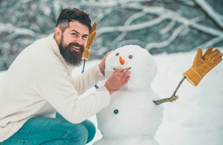 Photo for Funny snowmen. Happy smiling man make snowman on sunny winter day. People in snow. Snowman. Handsome Winter Man with snowman in frosty winter Park - Royalty Free Image