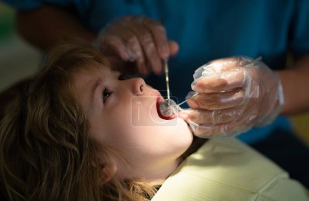 Photo for Kids stomatology and teeth care concept. Dentist checking little child patient teeth up at dental clinic. Close-up of little boy opening his mouth wide during inspection of oral cavity - Royalty Free Image
