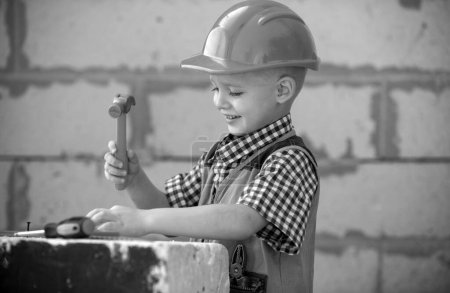 Téléchargez les photos : Petit garçon en casque de protection orange avec des instruments pour la rénovation. Réparation maison - en image libre de droit