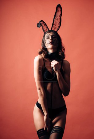 Foto de Feliz día de San Valentín. Morena posando desnuda usando orejas de conejo. Mujer con culo sexy posando usando orejas de conejo en el día de Pascua. Lindo conejito. Cara de expresión - Imagen libre de derechos