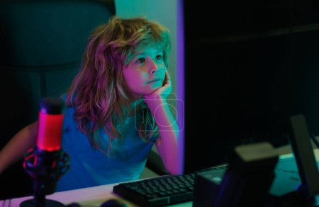 Foto de Niño usando PC por la noche. Niño con computadora en un cuarto oscuro. Retrato de un niño lindo mientras escribe en el teclado - Imagen libre de derechos