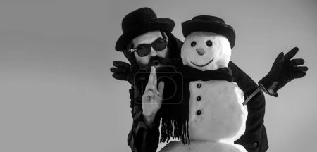 Téléchargez les photos : Drôle hiver bonhomme de neige en chapeau jouer avec bonhomme de neige en plein air. Homme avec bonhomme de neige sur fond d'hiver extérieur. Bonhomme de neige pour bannière d'hiver - en image libre de droit