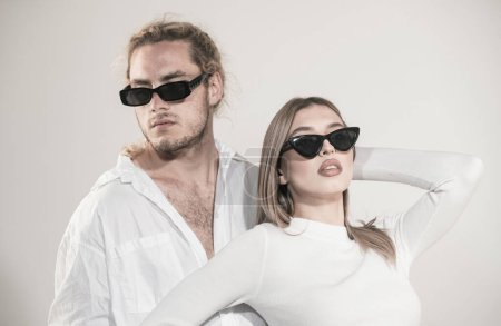 Photo for Couple in fashion black sunglasses. Young couple posing with sunglasses. Studio shot on gray background - Royalty Free Image