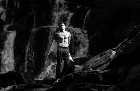 Photo for Muscular man going to swim in waterfall water. Flow of dollars. Profit business concept. businessman undressing at waterfall ready to swim. great finance waterfall. Wealth and success - Royalty Free Image