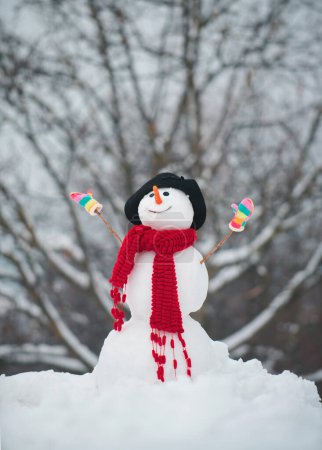 Foto de Lindos muñecos de nieve de pie en invierno paisaje de Navidad. Muñeco de nieve con una bolsa de regalos. muñeco de nieve de Navidad de cerca con bufanda - Imagen libre de derechos