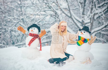 Photo for Happy winter time. Winter concept. Snowman and funny girl the friend is standing in winter hat and scarf with red nose - Royalty Free Image