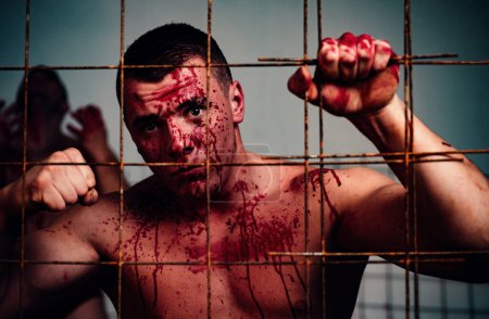 Photo for Psychic disease. Murderer brutal aggressive guy. Halloween concept. Aggressive person. Strong aggressive monster behind grid. Bodybuilder nude torso soiled blood. Prison for monster. Psycho mad man. - Royalty Free Image