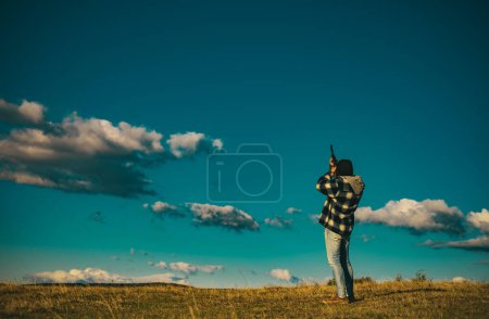 Photo for Hunter with Powerful Rifle with Scope Spotting Animals. Hunter with shotgun gun on hunt. Copy space for text. Most realistic hunting game ever created - Royalty Free Image