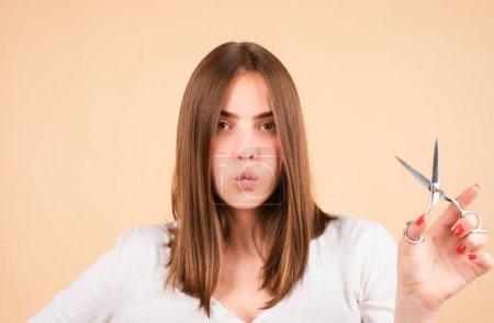 Photo for Woman with scissors having hair cut. Close up of a young woman with beautiful hair hold scissors, yellow background - Royalty Free Image