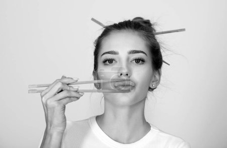 Photo for Funny young woman with chopsticks to roll in the mouth. Sexy lips with chopsticks - Royalty Free Image