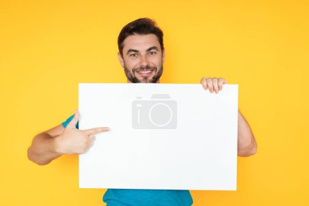 Photo for Man holds sign with copy space. Placard ready for copy space product. Sign to your copy space text. Man showing blank sign board on studio background, pointing finger. Empty copy space blank board - Royalty Free Image