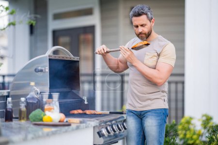 Photo for Grill and barbecue cook. Chef with BBQ cooking tools. Barbecue and grill. Picnic barbecue party. Chief cook with utensils for barbecue grill. Barbeque on holiday picnic. Man grilling a steak on BBQ - Royalty Free Image