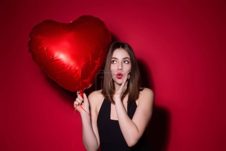 Photo for Beautiful young woman with heart shape air balloon on studio isolated background. Woman on Valentines Day. Heart of love. Girl hold red balloons heart. Holiday party, birthday. Heart love concept - Royalty Free Image