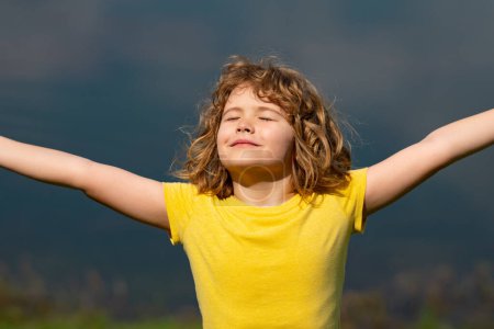 Photo for Little kid boy raising hands enjoying life and summer nature. Happy kid looking on summer sun. Fresh air, environment concept. Dream of flying. Summer seasonal outdoor. Carefree child enjoys summer - Royalty Free Image