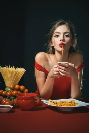 Photo for Young woman eating delicious pasta, enjoying tasty homemade spaghetti in kitchen interior. Pasta, Noodles, Linguine, Vermicelli. Sexy kitchen. Sexy woman on kitchen table. Kitchen menu. Italian food - Royalty Free Image