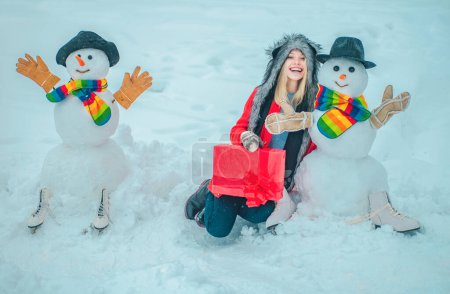 Téléchargez les photos : Les gens aiment l'hiver. Bonhommes de neige mignons avec fille d'hiver debout dans le paysage de Noël d'hiver. Happy girl portrait d'hiver - en image libre de droit