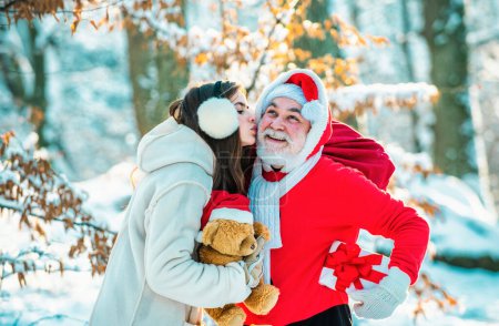 Foto de Nieve muchacha doncella besando a Santa. Santa Claus con chica. Paisaje invernal de bosque y nieve con santa claus - Imagen libre de derechos