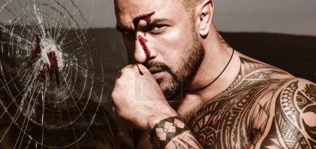 Foto de Pelea de puños. Artes marciales mixtas. Un hombre brutal y sangriento con un cuerpo tatuado. Hombre con el cuerpo muscular de perforación - Imagen libre de derechos
