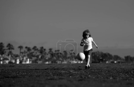 Téléchargez les photos : Enfant garçon jouant au football sur le terrain de football. Un gamin qui joue au foot. Football d'entraînement pour enfants - en image libre de droit