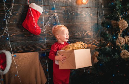 Foto de Niño feliz con un regalo de Navidad sobre fondo de madera. Feliz Navidad. Fiesta de celebración. Niños de Navidad - concepto de felicidad. Año nuevo niños - Imagen libre de derechos