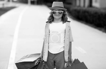 Téléchargez les photos : Enfant avec sacs à provisions. Mode et vente. Petit acheteur client - en image libre de droit