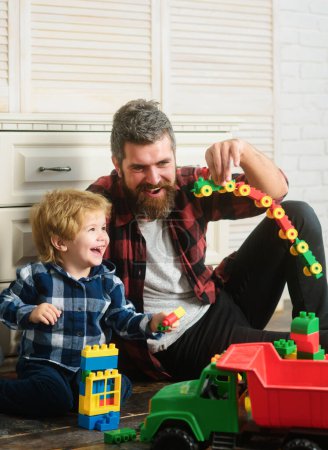 Foto de Padre e hijo crean juguetes de ladrillos. Papá y el niño construyen bloques de plástico. Familia feliz, día del padre - Imagen libre de derechos