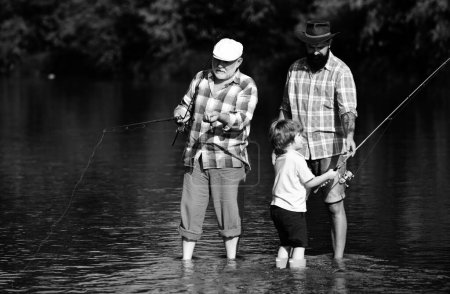 Foto de Pescadores. Pesca con mosca de trucha. Padre enseñando a su hijo a volar peces en el río. Abuelo y padre con niño lindo niño están pescando - Imagen libre de derechos