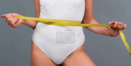 Photo for Woman weight loss. Woman holding the meter and measuring waist - Royalty Free Image