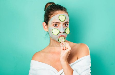 Photo for Sexy young girl with a mask for skin and slices of cucumbers on face. Happy mood and selfcare. Natural beauty concept. Beautiful woman with off shoulders eats a cucumber - Royalty Free Image