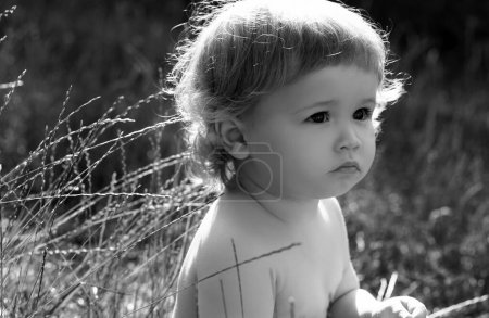 Foto de Bebé niño en hierba verde en el césped de primavera. Niños pequeños en el parque. Cara de bebé de cerca. Gracioso retrato de primer plano de niño. Niño rubio, cara de emoción - Imagen libre de derechos