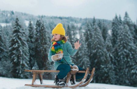 Photo for Boy sledding, enjoying sleigh ride. Child sitting on the sleigh. Children play with snow - Royalty Free Image