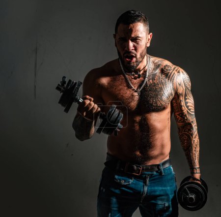 Photo for Excited sexy muscular man with dumbbell. Athletic man doing exercises with dumbbell at biceps. Sporty man with naked torso. Strength and motivation - Royalty Free Image