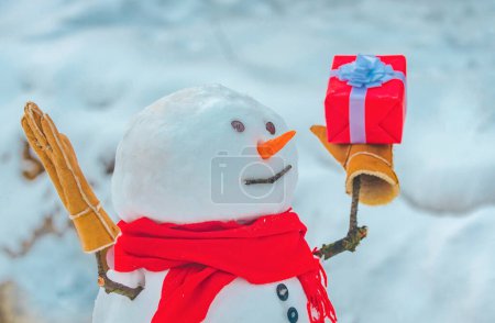 Foto de Muñeco de nieve con bolsa de compras y regalo en el fondo de nieve blanca. Saludo muñeco de nieve. Feliz Navidad y feliz año nuevo tarjeta de felicitación con espacio para copias - Imagen libre de derechos