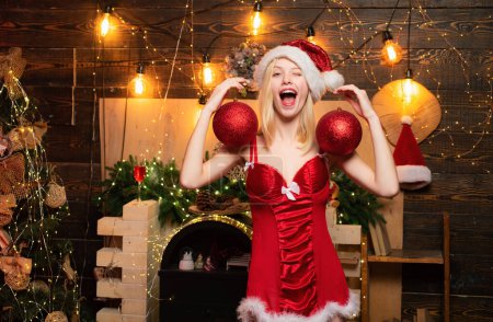 Photo for Pretty sexy blonde new year young woman in christmas santa red hat with fur in corset holding decoration ball. Christmas gifts. Family winter holidays, sales and people concept - Royalty Free Image