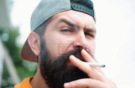 Photo for Hipster brutal man smoking cigarette. Smoking addiction - Royalty Free Image
