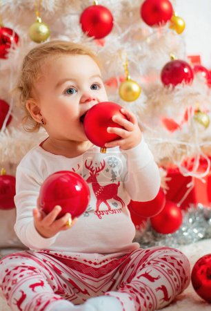 Photo for Child with a Christmas present on wooden background. Happy children. Christmas Babies. Christmas children. Cute little child is decorating Christmas tree indoors - Royalty Free Image
