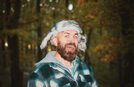 Téléchargez les photos : Un homme heureux avec des lièvres dans un parc d'automne. Portrait d'un jeune homme souriant en vêtements chauds frissonnant lors d'une promenade en forêt le jour d'automne. Drôle d'expression - en image libre de droit