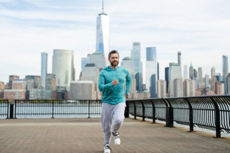 Foto de Hombre corredor. Un deporte saludable. Hombre corriendo en la ciudad de Nueva York. El corredor de fitness está corriendo cerca de Manhattan. Un tipo corriendo por la calle americana. Un hombre corriendo en Nueva York con ropa deportiva. Ropa deportiva para corredores - Imagen libre de derechos