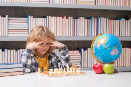 Foto de Un niño listo pensando en ajedrez. Retrato de niño inteligente con tablero de ajedrez - Imagen libre de derechos