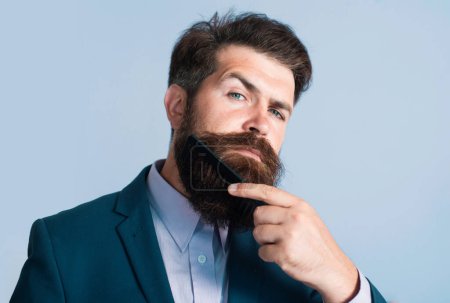 Foto de Cuidado de la barba. Primer plano de un joven que se peina la larga barba. Barbudo hombre con barba, barbudo gay. Concepto de barbería - Imagen libre de derechos